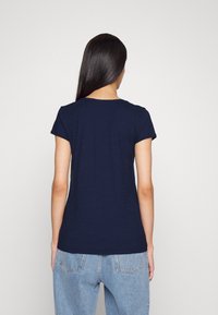 Marineblaues T-Shirt mit kurzen Ärmeln und Rundhalsausschnitt, lässige Passform, aus weichem Stoff, von hinten vor einem schlichten Hintergrund präsentiert.