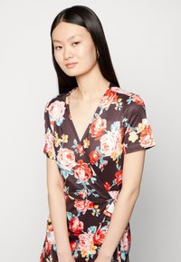 Vestido floral envolvente em tecido castanho escuro, apresentando rosas vermelhas e azuis, mangas curtas e um decote em V. Textura suave e forma ajustada.