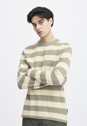 Striped sweater in beige and olive green, made of knit fabric. Features a round neckline and long sleeves with ribbed cuffs and hem.
