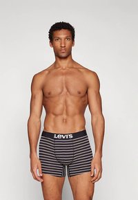 Boxer briefs à rayures noires et blanches avec une ceinture marquée. Le tissu semble doux et extensible, conçu pour le confort et un bon ajustement.