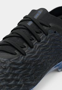 Scarpe da calcio nere con una superficie testurizzata a motivo ondulato, lacci neri e accenti blu lungo la parte superiore e i lati.