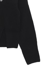 Maglione nero a maglia con texture a costine, scollatura ampia e spacchi sull'orlo. Il tessuto è morbido e leggermente testurizzato.