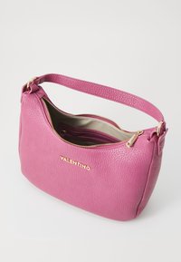 Pink textured leather Valentino handbag with a single strap, gold zipper partially open, and gold logo on the front.