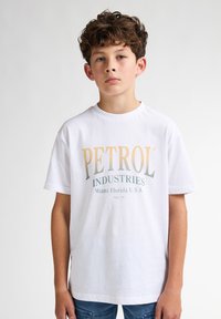Camiseta blanca de algodón con gráfico "PETROL INDUSTRIES" en colores degradados. Manga corta y cuello redondo con un corte relajado.
