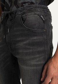 Černé denimové joggery s elastickým pasem, stahovací šňůrkou, designem s pěti kapsami, jemným blednutím a štítkem se značkovým logem "Replay".