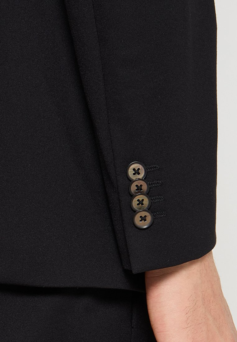 Manica di giacca nera con quattro bottoni e cuciture dettagliate, che mostra un design su misura.