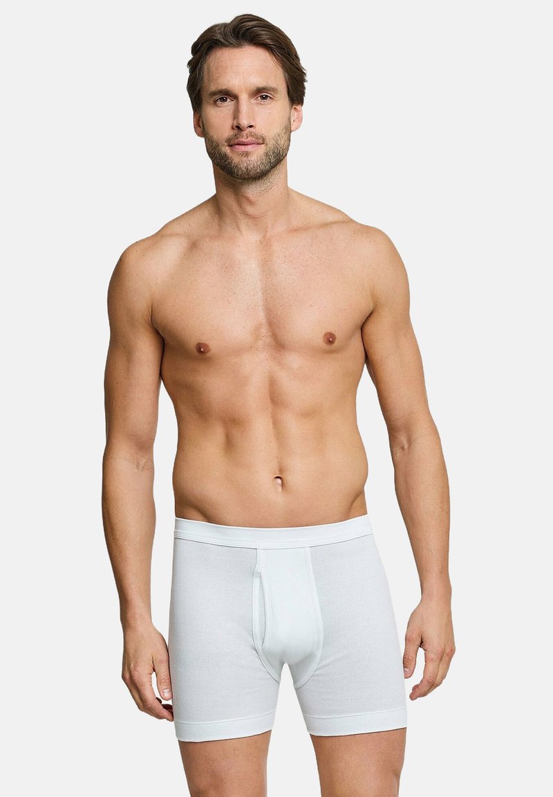 White cotton boxer shorts with a ribbed texture and a fitted design. Features a front fly opening and elastic waistband.