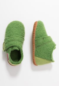 Zielone filcowe klapki z rzepem, gumową podeszwą, okrągłym noskiem i miękką teksturą. Akcentowane jaśniejszym zielonym materiałem na obcasie.