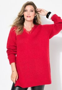Czerwona, oversize dzianinowa bluza z dekoltem w kształcie litery V i koronkowymi wykończeniami. Długie rękawy z prążkowanymi mankietami i dołem, wykonana z grubej włóczki. Gładka faktura.