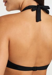 Black halter bikini top with a tied neck strap and a smooth texture, featuring a clasp closure at the back.