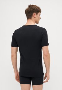Schwarzes T-Shirt mit kurzen Ärmeln aus weichem Stoff, mit Rundhalsausschnitt und geradem Schnitt, minimalistisch gestaltet.