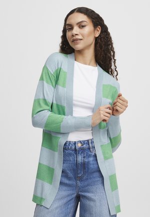 Hellblauer Cardigan mit vertikalen grünen Streifen, offener Vorderseite, langen Ärmeln und gerippten Bündchen, über einem weißen Hemd getragen.