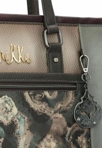 Nahaufnahme einer mehrfarbigen Handtasche mit strukturierten Paneelen, einem Metallreißverschluss, einem goldenen Markenlogo und einem schwarzen Metallschlüsselanhänger, der an einem Riemen befestigt ist.
