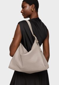 Light gray leather hobo bag with a textured finish, wide top opening, and a single shoulder strap secured by a gold-tone accent.