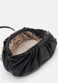 Sort plisseret håndtaske lavet af blødt materiale, med en beige inderside med "GUESS" logo mønster og en lynlås i guldfarvet metal.