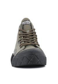 Green canvas sneaker with brown laces, rubber black toe cap, textured outsole, and mesh detailing on the tongue. Logo visible on the tongue.