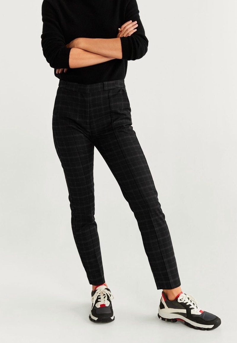 Pantalon noir à motif à carreaux avec une coupe slim, présentant une texture lisse et une taille haute. Assorti à des baskets noires et blanches.