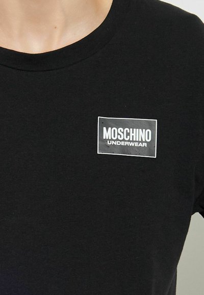 Maglietta nera con un piccolo logo rettangolare bianco sul petto con la scritta "MOSCHINO UNDERWEAR" in lettere maiuscole.