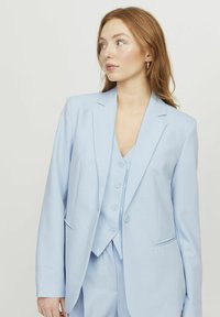 Hellblau maßgeschneiderte Blazer mit Revers, einreihiger Knopfverschluss und Fronttaschen, kombiniert mit einer passenden Weste mit Knopfdetails.