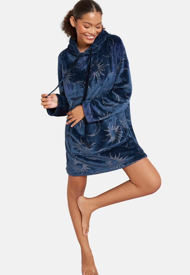 Granatowa welurowa sukienka z kapturem, długimi rękawami i luźnym krojem, ozdobiona srebrną haftowaną grafiką słońca i księżyca. Miękka w dotyku, z kieszenią typu kangur.