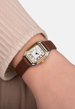 Bracelet de montre en cuir texturé marron avec un boîtier rectangulaire en argent et or, un cadran blanc et des chiffres romains noirs. Couronne dorée sur le côté.