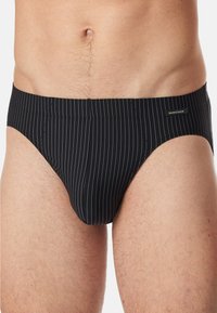 Schwarzgestreifte Schwimmshorts aus dehnbarem Stoff. Sie verfügen über einen niedrigen Bund, Seitennähte und ein kleines Logotag am Bund. Glatte Textur.