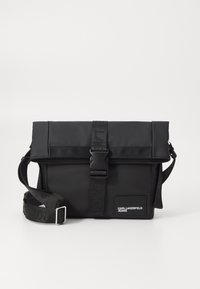 Borsa a tracolla nera con chiusura a pattina, realizzata in materiale liscio. Caratterizzata da una tracolla regolabile, hardware a fibbia e logo sul fronte.