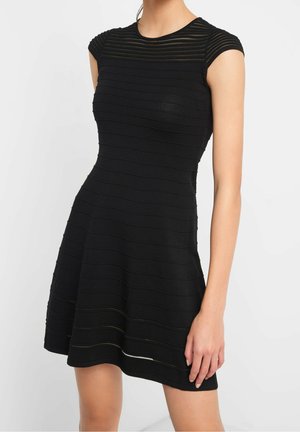 Robe noire avec texture côtelée horizontale, manches courtes, et corsage ajusté évasé en jupe, fabriquée à partir d'un tissu extensible.