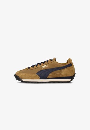 Sneaker in suede marrone con dettagli blu navy, suola intermedia bianca, suola esterna in gomma testurizzata e dettagli cuciti. Logo Puma sul lato.