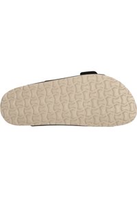 Sula av sko med en strukturerad ljusbeige gummiyta, som har ett vågformat mönster för grepp och stabilitet. Mörka kanter omger sulan.