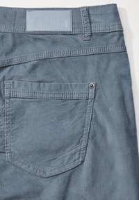 Blå bomullshängselbyxor med en ficka i patchstil, med kontrastsömmar och en logotyppräglad läderetikett vid midjan. Strukturerad tygkvalitet.