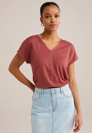 Top de color óxido, de manga corta y con escote en V, hecho de una tela suave y texturizada, combinado con una falda de mezclilla ligera de color azul con una abertura frontal.