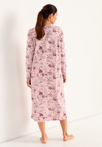 Lång rosa nattlinne med blommönster och långa ärmar. Har en avslappnad passform, mjuk textur och rund halsringning.
