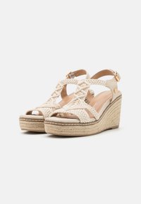 Sandalias de cuña con tiras de tela trenzada, color beige claro, que presentan una suela de plataforma envuelta en cuerda y detalle de hebilla en el tobillo.