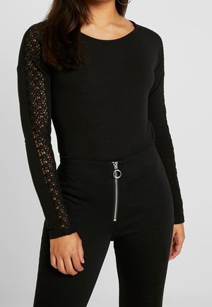 Czarny body z długim rękawem z koronkowymi zdobieniami na rękawach i zamkiem błyskawicznym z przodu, o dopasowanym kroju i elastycznym materiale.