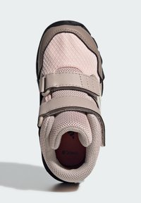 Zapatilla deportiva de color rosa claro y beige con parte superior de malla, suela negra y dos correas ajustables de velcro para un ajuste seguro.