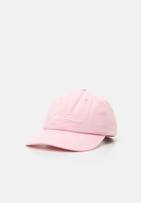 Pink baseball cap made of cotton, featuring a curved brim and embroidered white signature on the front. Six ventilation eyelets visible.