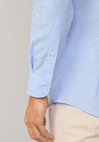 Lichtblauw gestreepte lange mouwen shirt met knoopmanchetten, met een zachte textuur en een licht gebogen zoom.