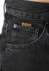Svarte denimjeans med G-Star Originals-merke, synlige sømmer og en liten baklomme med metallknapp.