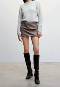 Suéter gris borroso, mini falda marrón de cuadros y botas negras altas con tacón. Textura suave con diseño ajustado y patrones sutiles.