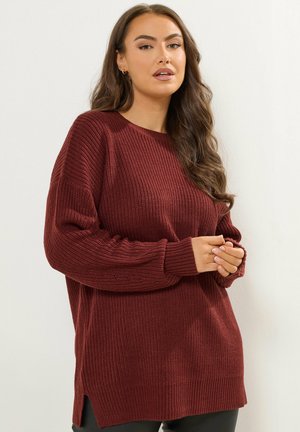 Suéter de punto burdeos con textura acanalada, cuello redondo y mangas largas. Las aberturas laterales en el dobladillo mejoran la comodidad y el ajuste.