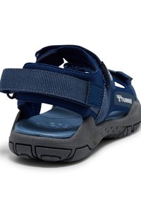 Mørkeblå sandal med justerbare stofremme, struktureret gummisål, formet fodseng og forstærket hæl for støtte.