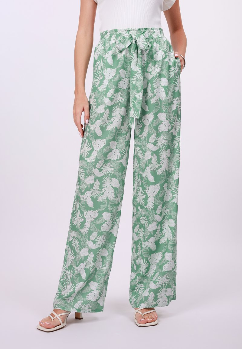 Pantalones amplios y fluidos en verde claro, con estampados botánicos en blanco. Cintura elástica con un lazo, tejido suave y bolsillos laterales.