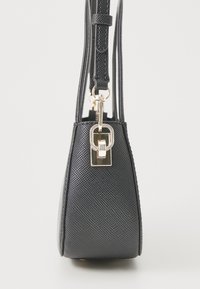 Sac à main noir avec une finition texturée, une forme angulaire et un accent de serrure en métal doré. Bandoulière réglable pour plus de polyvalence.