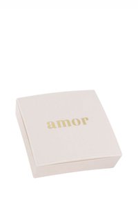 Beige fyrkantig smyckeslåda med guldtexten "amor" centrerad på locket, stängd och visad från en vinkel.