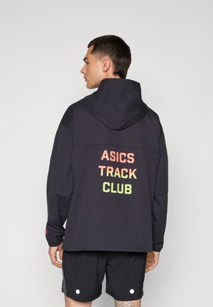Musta huppari, jossa lukee "ASICS TRACK CLUB" oranssilla ja vihreällä gradienttitekstillä selkäpuolella. Ominaisuuksiin kuuluu pitkät hihat ja rento istuvuus.