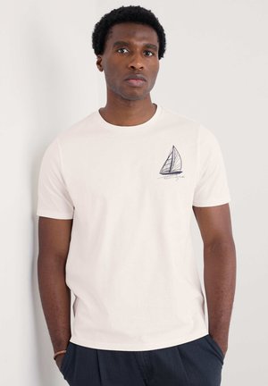 Weißes Baumwoll-T-Shirt mit Rundhalsausschnitt, das ein blaues Segelboot-Design auf der linken Brust zeigt. Kurze Ärmel und eine lockere Passform.