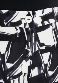 Černo-bílé abstraktní vzorované tkaniny se zapínáním na knoflík v pase; hladká struktura a přizpůsobený střih.