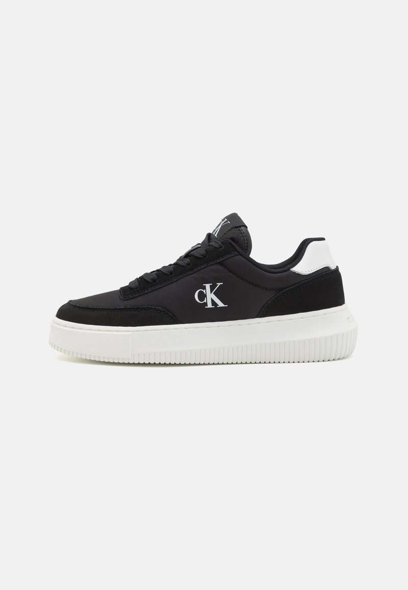 Fekete sneaker fehér talppal, sima felsőrésszel, kontrasztos hátsó sarokkiemeléssel és oldalsó logóval. Fűzős kialakítás.