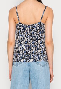 Top bez rukávů s abstraktním vzorem v modré, černé a krémové barvě, vyrobený z lehkého materiálu s uvolněným střihem a nastavitelnými ramínky.